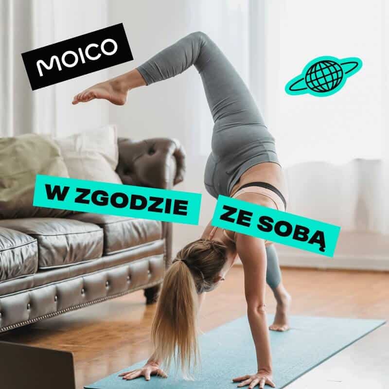 Na grafice widzimy kobietę wykonującą dynamiczną pozycję jogi — balansuje na dwóch dłoniach i jednej stopie, podczas gdy jedna noga jest uniesione w powietrzu. Cała scena rozgrywa się w przytulnym wnętrzu: drewniana podłoga, skórzana kanapa, ciepłe światło. Osoba ubrana jest w szare sportowe legginsy i top, co podkreśla klimat skupienia i harmonii. Pojawiają się dwa napisy — „MOICO” oraz „W ZGODZIE ZE SOBĄ”, czyli hasło zachęcające do życia w równowadze ze sobą i otoczeniem.