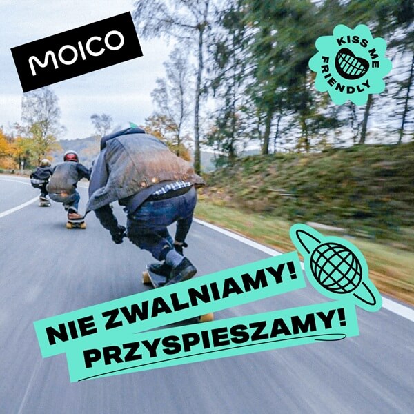 Zdjęcie przedstawia dynamiczną scenę jazdy na longboardach wśród jesiennych drzew i pagórków. Grupa osób pędzi w dół asfaltowej drogi, a efekt rozmycia ruchu podkreśla prędkość i energię chwili. Uczestnicy są wyposażeni w kaski i ochraniacze, co sugeruje sportową pasję połączoną z dbałością o bezpieczeństwo. Na grafice widnieją kolorowe elementy: logo „MOICO”, hasło „NIE ZWALNIAMY! PRZYSPIESZAMY!” oraz zabawne znaki graficzne, które dodają całości młodzieżowego charakteru. 