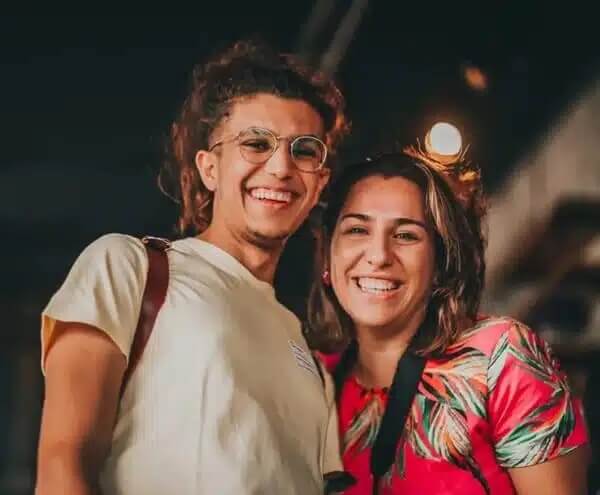 Dwie uśmiechnięte osoby pozują razem do zdjęcia w wieczorowej scenerii. Na ich twarzach widać radość i swobodną atmosferę wspólnie spędzanego czasu.